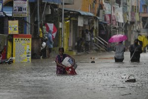 People wade through a flooded street during heavy rain in Chennai, India, Tuesday, Oct.15, 2024.