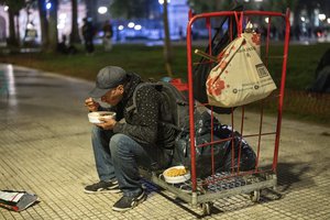 A man eats a meal provided by a nongovernmental organization at Plaza de Mayo square, in front of the presidential palace in Buenos Aires, Argentina, Monday, Oct. 7, 2024.