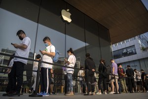 FILE - Customers line up outside of an Apple Store before its opening on the first day of sale for the Apple iPhone 14 in Beijing, China on Sept. 16, 2022.