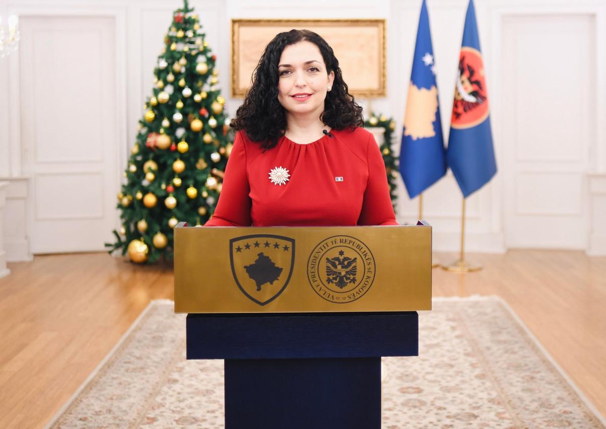 Vjosa Osmani es la presidenta de Kosovo. Habla ante la bandera del país y la enseña albanesa.