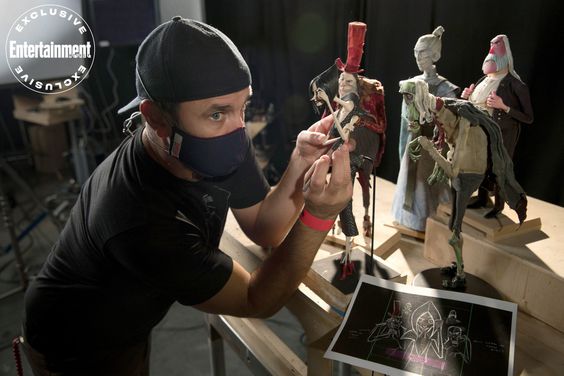 Masked animator posing puppets