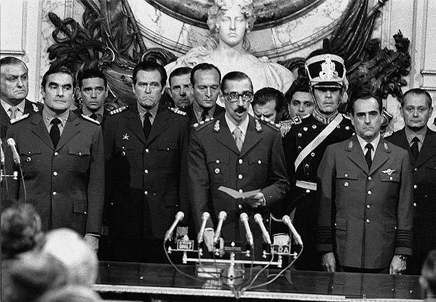 Ladeado por Emilio Massera (esq.) e Orlando Agosti, o general Videla � empossado presidente, cinco dias ap�s o golpe