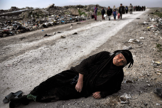 -- AFP PICTURES OF THE YEAR 2017 -- An Iraqi woman lies on the ground as civilians flee Mosul while Iraqi forces advance inside the city during fighting against Islamic State group's fighters on March 8, 2017. Supported by US-led air strikes, the forces have made steady progress in their battle to seize Iraq's second city from the Islamic State group, announcing the recapture of two more areas. Hundreds of thousands of civilians are believed to still be trapped under jihadist rule in the Old City, where Abu Bakr al-Baghdadi proclaimed a "caliphate" in his only public appearance in July 2014. / AFP PHOTO / ARIS MESSINIS ORG XMIT: ARIS3059