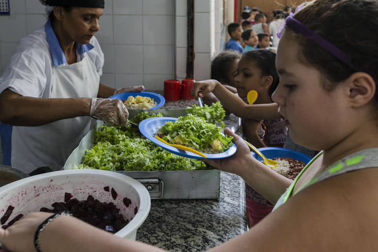 Crianças se servem de salada e outros alimentos em cantina de escola