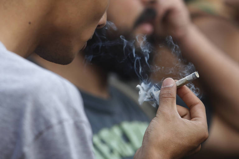 Jovem fuma um cigarro de maconha durante uma marcha pela legalização da droga