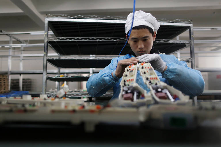 Trabalhador em fábrica de eletrônicos da China; compra em massa da Huawei contribui para desabastecimento global
