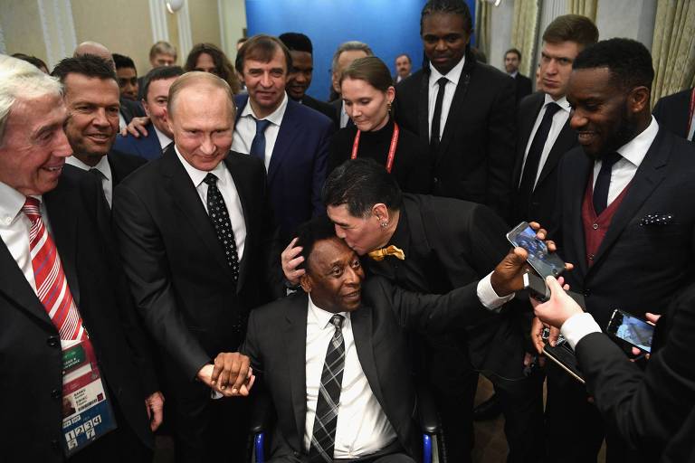 O presidente da Rússia, Vladimir Putin, segura a mão de Pelé, que recebe beijo de Maradona, em Moscou