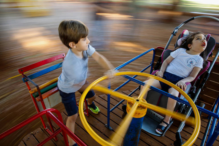 Maria Eduarda, 10, brinca com o irmão, João, 6 em playground inclusibo