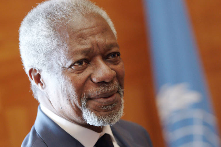 Close de Kofi Annan, de terno cinza, diante da bandeira da ONU