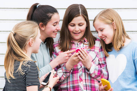 Group Of Young Girls Outdoors Looking At Message On Mobile Phone DIREITOS RESERVADOS. NÃO PUBLICAR SEM AUTORIZAÇÃO DO DETENTOR DOS DIREITOS AUTORAIS E DE IMAGEM