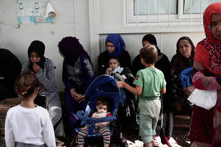 FILE PHOTO: Women and children sit at the Moria camp for refugees and migrants on the island of Lesbos