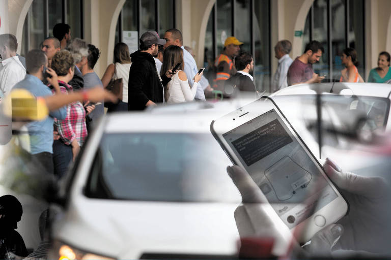 Montagem em foto de passageiros que aguardam carros de aplicativos no desembarque do aeroporto de Congonhas, na zona sul de São Paulo 