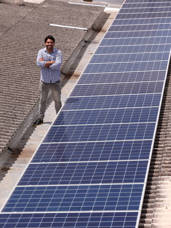 Vinicius Ferraz com placa instalada no teto da sede da Solar 21, em Brasília