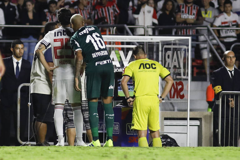 Jogadores do Palmeiras e do São Paulo aguardam enquanto o árbitro consulta o VAR em partida no estádio do Morumbi, em São Paulo