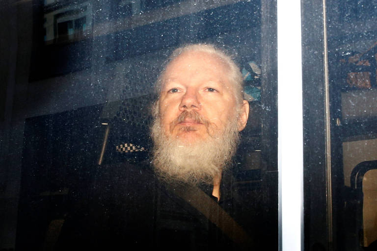 Julian Assange, em van da polícia, após ser preso em Londres

