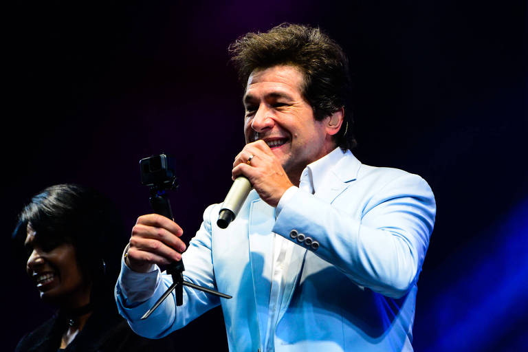 Daniel canta de terno azul claro e sorridente em show no Santuário Nacional de Aparecida/SP
