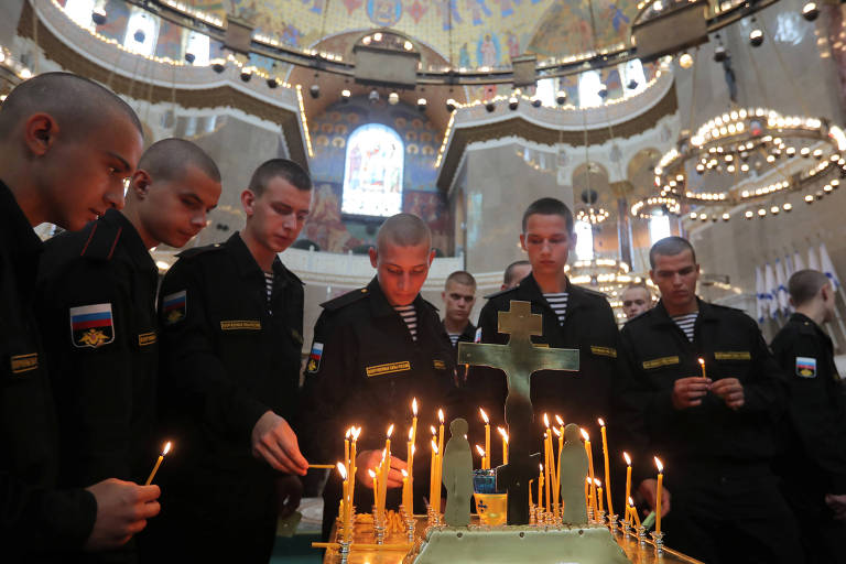 Marinheiros acendem velas em homenagem aos mortos no acidente, na Catedral Naval de Kronstadt, cidade russa