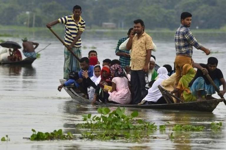 Homens e mulheres em barco em meio a inundação