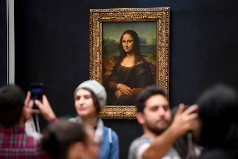 Pessoas tirando selfies com 'Mona Lisa' ao fundo em parede escura