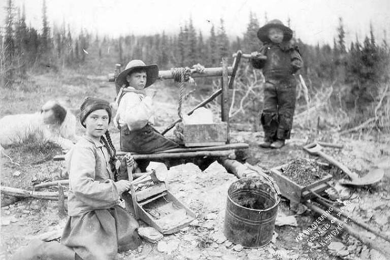 Três crianças trabalham em uma mina de ouro em Dominion Creek, no Canadá, em 1898