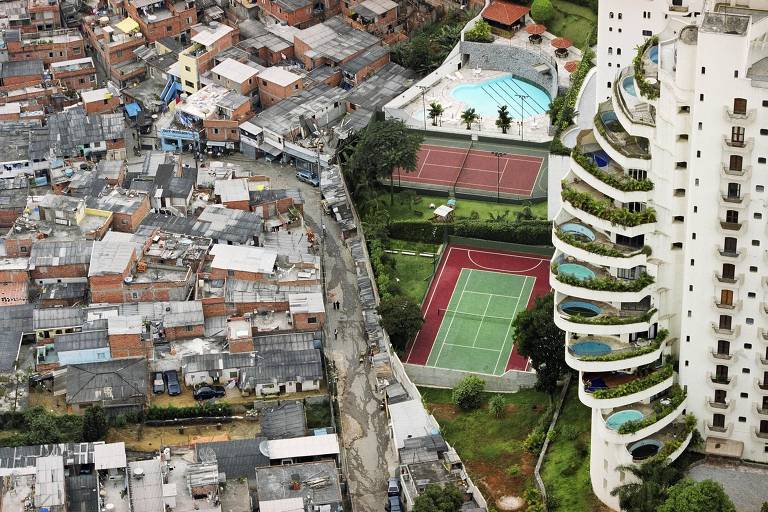 prédio com piscinas cheias e quadras de esporte novas contrastam com área de favela