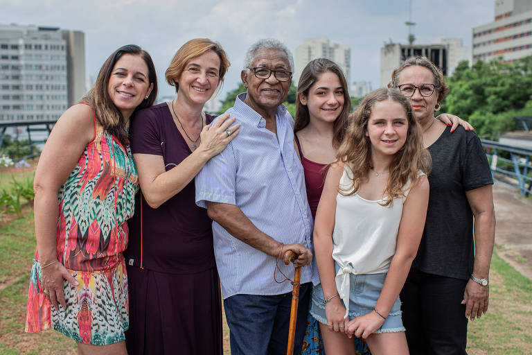 Retrato do venezuelano Raul Escalona e sua mulher, Elvira Barroso (de preto), com sua família brasileira; todos abraçados olhando para a câmera