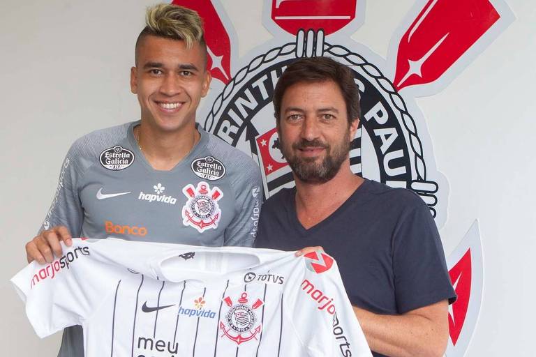 O diretor de futebol do Corinthians, Duílio Monteiro Alves, acompanhado do  volante Victor Cantillo, segura a camisa do clube