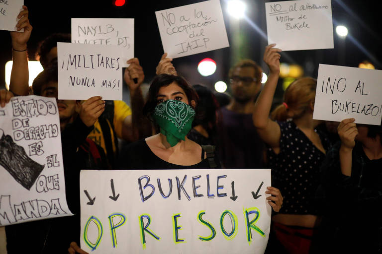 Manifestante contrária ao governo salvadorenho segura cartaz com os dizeres 'Bukele opressor' em protesto no Congresso Nacional, em San Salvador