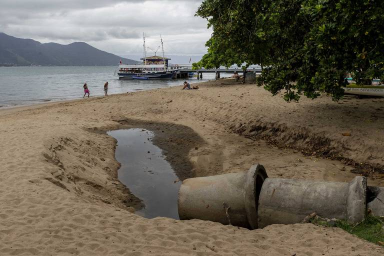 Cano despeja água na praia, que moradores dizem estar poluída