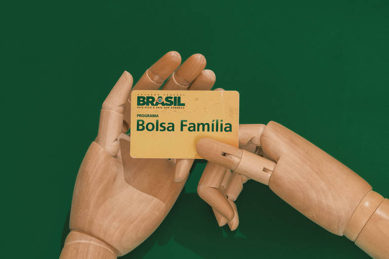 Mão de boneco segura cartão do Bolsa Família