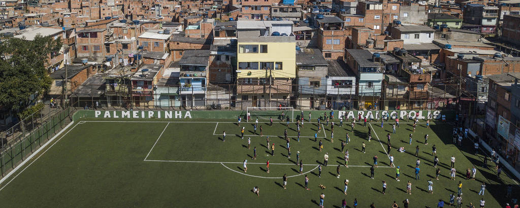 Mantendo espaço entre si, líderes de ruas da favela Paraisópolis se reúnem  no campo de futebol da favela para receber doação de sabão em barra e álcool em gel que serão repassados para os moradores