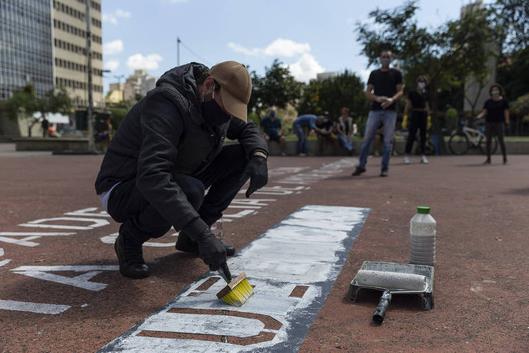 Imagem mostra Victor Ghiraldini, 42, produtor gráfico do Estúdio Miolo, que teve a ideia de pintar frases motivacionais seguidas pela #fiqueemcasa, durante ação na praça Roosevelt; ao todo, 25 pontos da cidade vão receber as intervenções artísticas, que têm apoio da Prefeitura de São Paulo