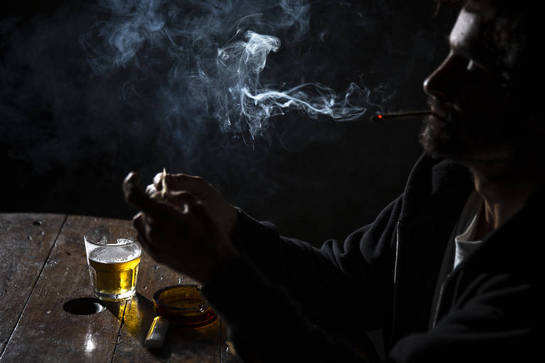 homem bebe cerveja e fuma um cigarro