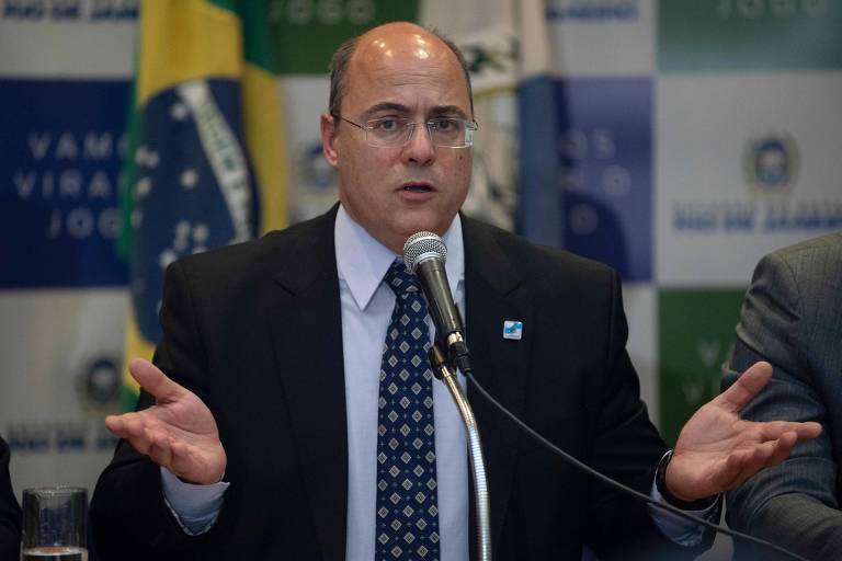 Witzel falando ao microfone e fazendo gesto com as duas mãos