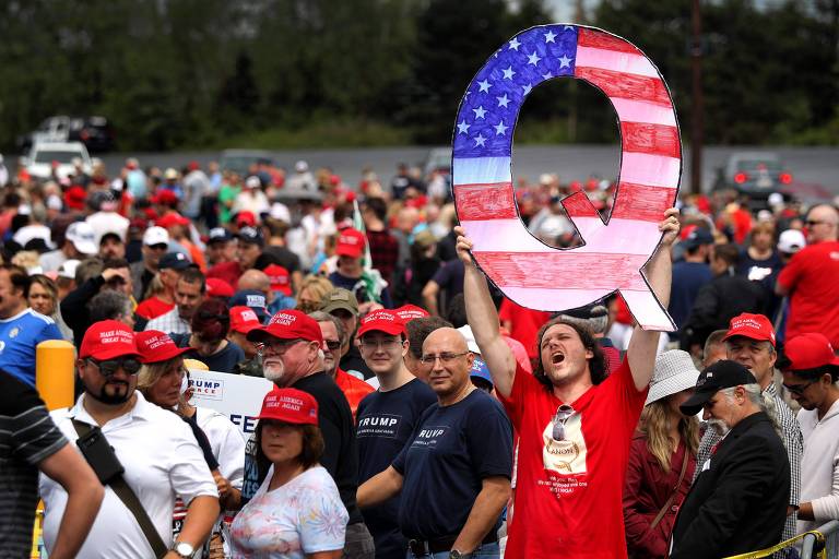 Apoiador de Donald Trump segura letra 'Q' com a bandeira americana enquanto aguarda o presidente em um comício na Pennsylvania