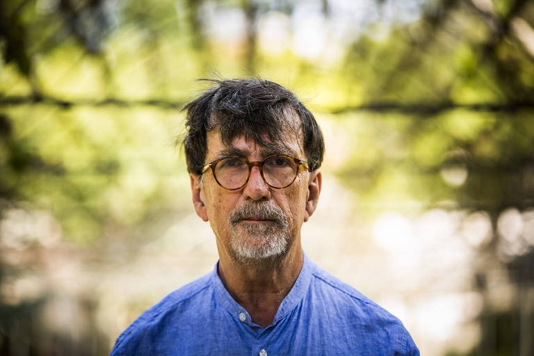 Bruno Latour olhando para frente com vegetação ao fundo