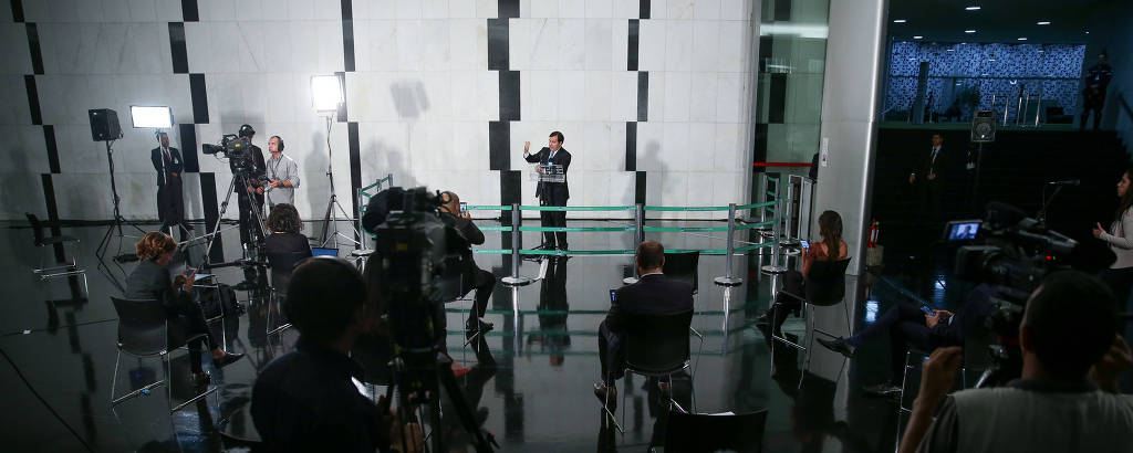 O presidente da Câmara, Rodrigo Maia, segue o novo protocolo sanitário em entrevista coletiva: repórteres ficam afastados e sentados em cadeiras distanciadas uma da outra