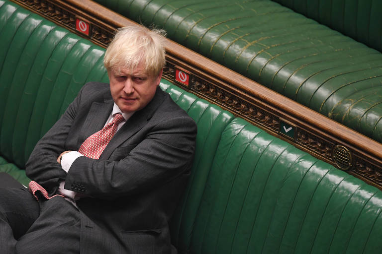 Sentado, de braços cruzados e expressão contrariada, Boris Johnson escuta debate no parlamento