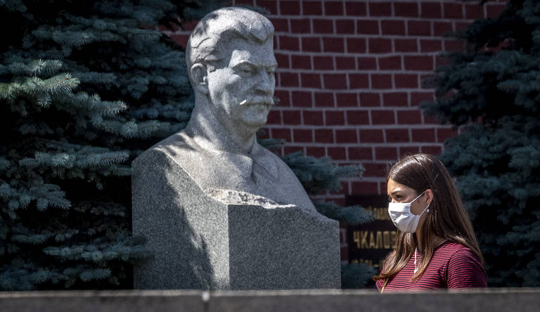 Mulher passa na frente do túmulo de Stálin, nas muralhas do Kremlin, centro de Moscou