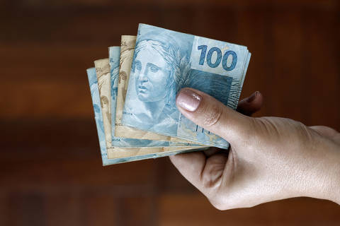 Hands holding Brazilian real notes, money from Brazil, notes of Real, Brazil BRL banknote, Brazilian currency, economy and business.