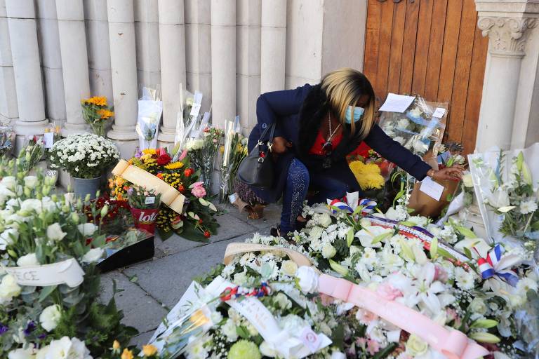 Entrada de igreja com várias flores, mulher coloca flores também