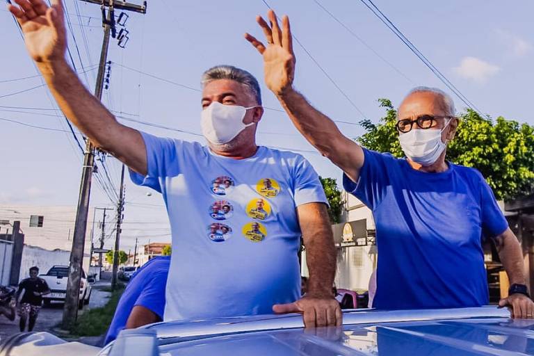 dois homens de máscara acenam em carreata