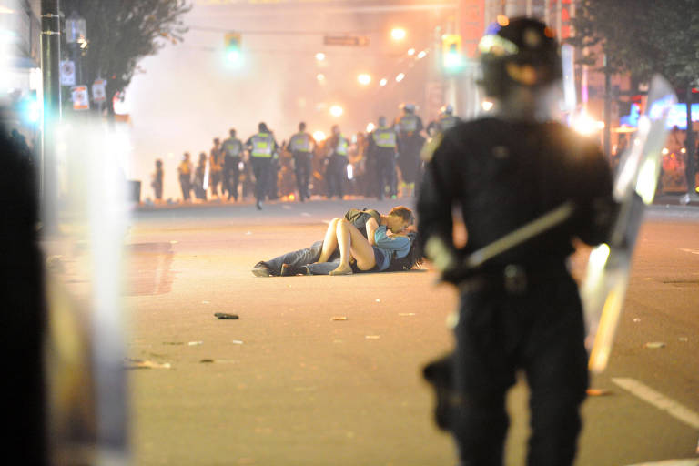 Casal se beija no chão durante um confronto entre policiais e torcedores em Vancouver, no Canadá