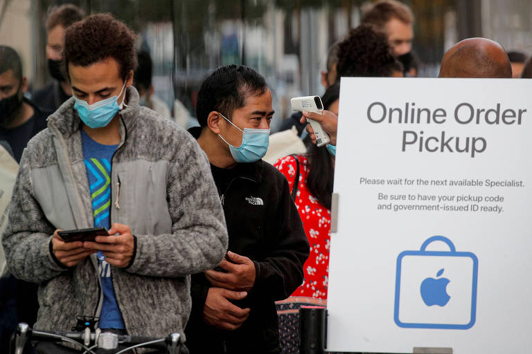 Clientes testam a temperatura enquanto esperam na fila do lado de fora da Apple Store do Brooklyn, em Nova York, para receber os aparelhos do novo iPhone 12 durante a pandemia de coronavírus