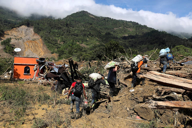 Moradores carregam pertences que conseguiram salvar de deslizamento de terra causado pelo furacão Eta, no vilarejo de Queija, no departamento de Alta Verapaz, na Guatemala