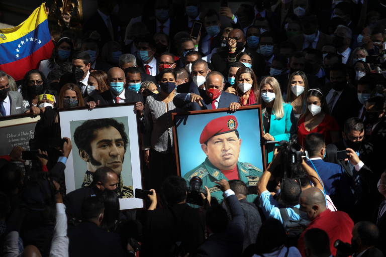 Deputados alinhados ao regime de Maduro seguram retratos de Simón Bolívar e Hugo Chávez durante sessão da nova Assembleia Nacional