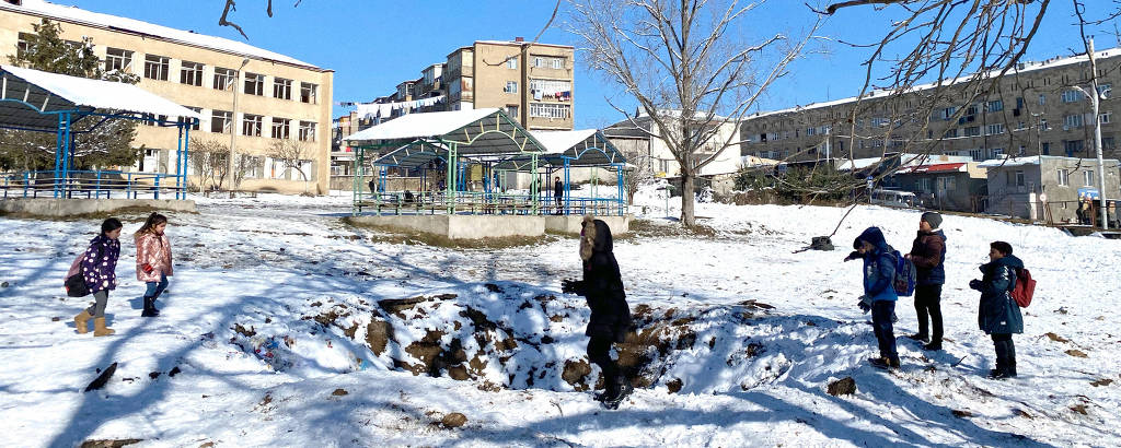 Crianças brincam em cratera causada por uma granada durante bombardeio em escola de Stepanakert, capital de Nagorno-Karabakh, interditada após o fim do conflito