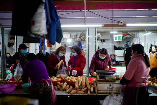 People wearing face masks buy lotus roots at a wet market, following an outbreak of the coronavirus disease (COVID-19) in Wuhan