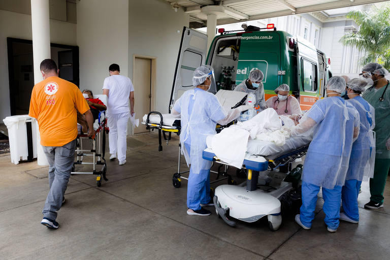 Imagem mostra equipe de saúde com uniformes azuis atendendo paciente em maca na chegada ao hospital