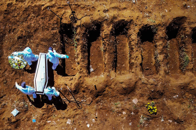 Sepultadores trabalham em covas abertas no cemitério de Vila Formosa, em São Paulo